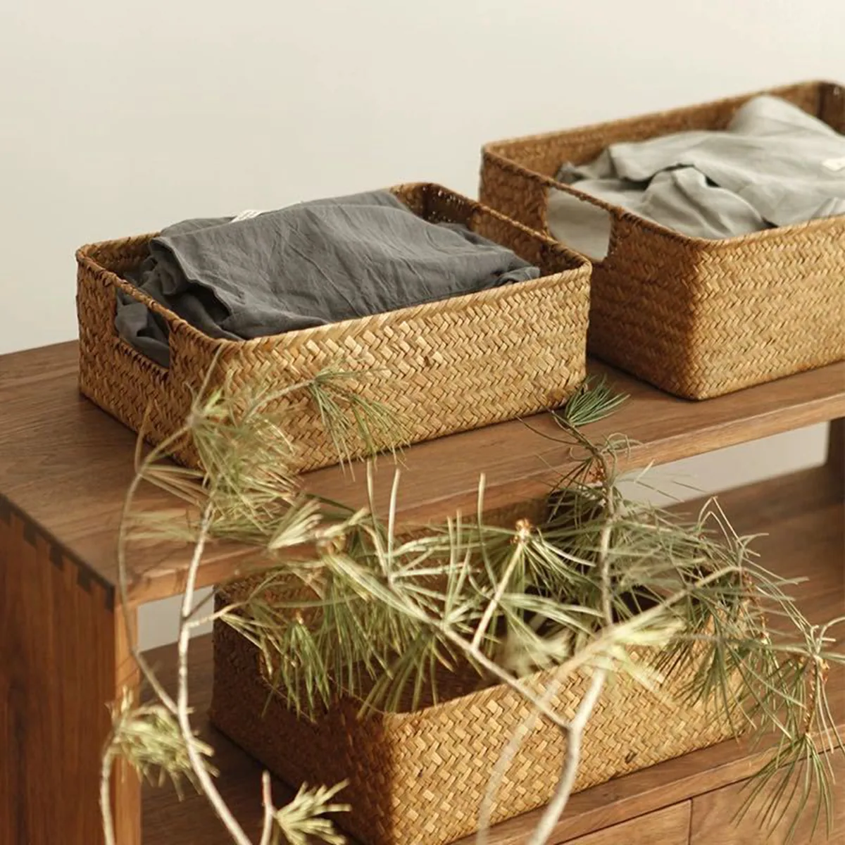Paniers Kago en jonc de mer tressé garnis de linge, sur un banc en bois