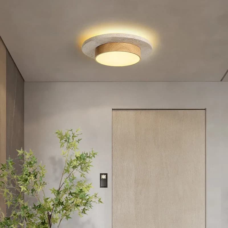 Plafonnier Yūgen en travertin et bois dans une entrée, halo de lumière chaude