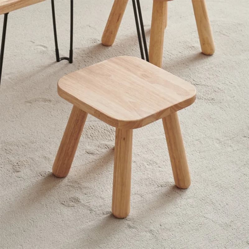 Tabouret Ki en bois massif clair, assise carrée aux angles arrondis, posé sur un tapis beige