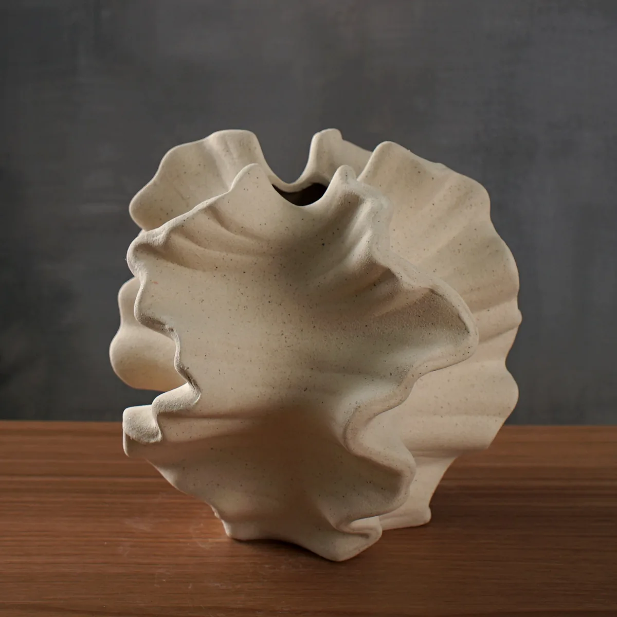 Vase Sango en céramique beige mate, forme ondulée de corail, sur une table en bois